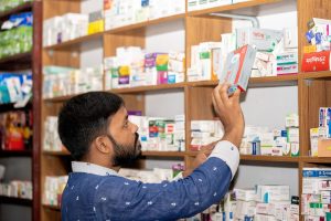 Pharmacist placing boxed medicines on pharmacy shelves
